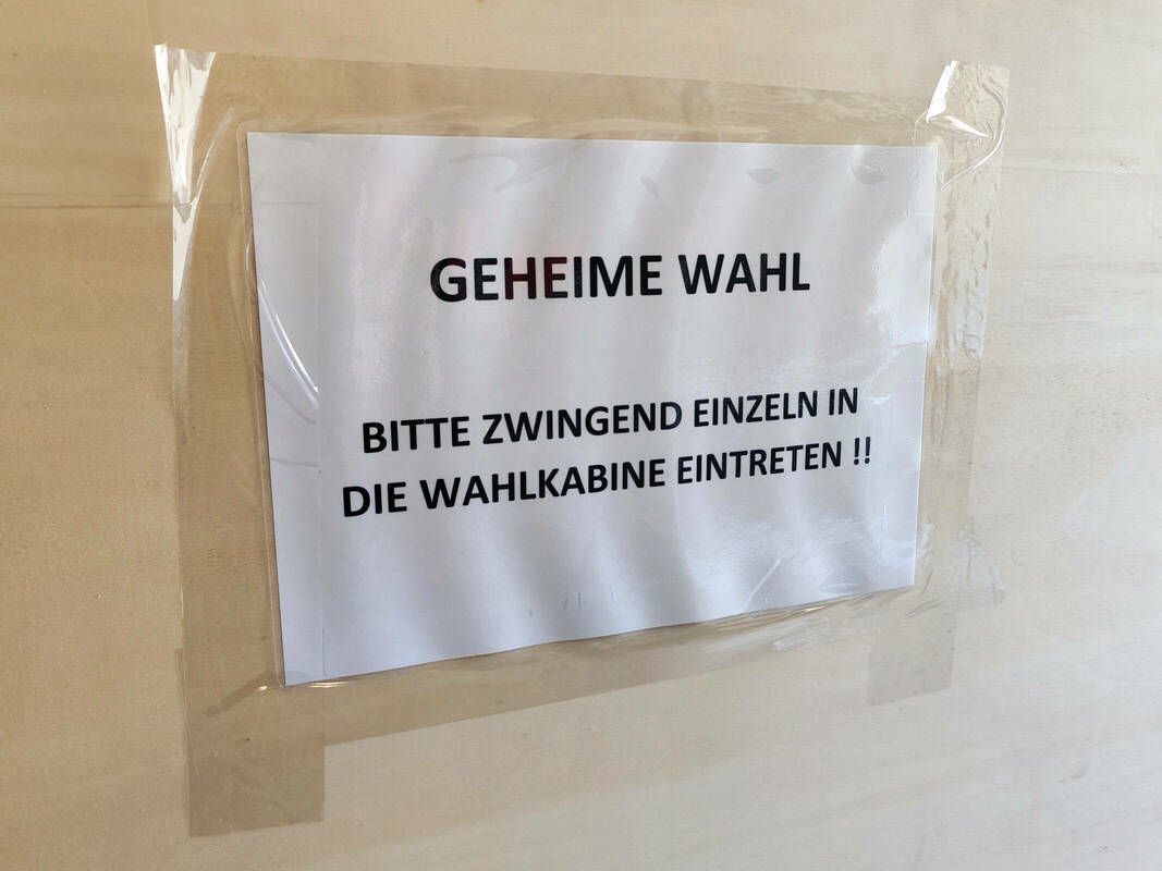 Wahlkabine mit Aufdruck "Geheime Wahl - Bitte einzeln eintreten"