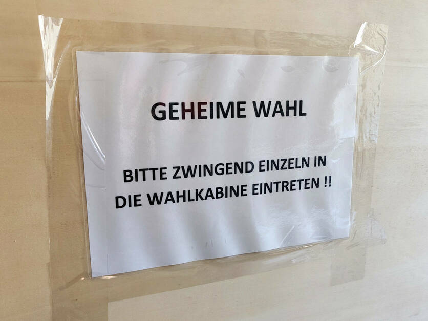 Wahlkabine mit Aufdruck "Geheime Wahl - Bitte einzeln eintreten"