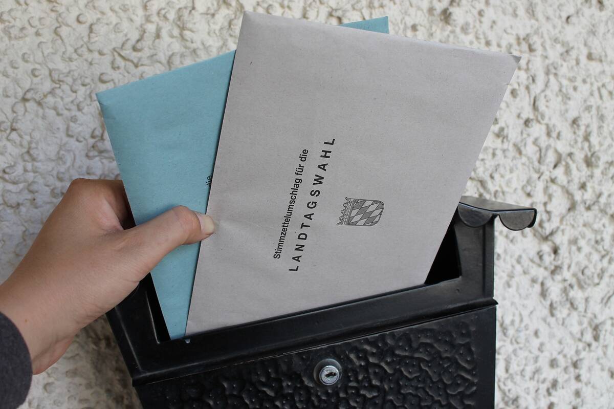 Briefwahlumschlag in den Briefkasten stecken